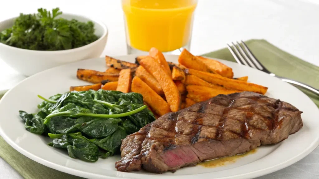 Breakfast plate with steak, sweet potato fries, and sautéed spinach.